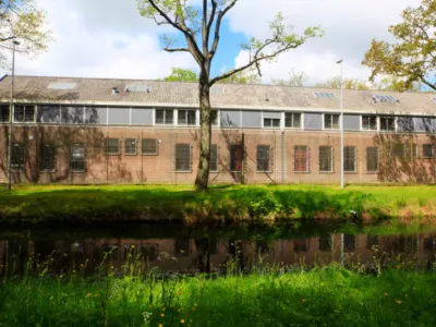 Photo d'une prison devant un cours d'eau. table ronde Association L'Aruche, Notre affaire à tous, Observatoire international des prisons, Ligue des Droits de l'Homme, fne ILE DE FRANCE, écologie et droits humains, justice sociale et environnementale. Lutte contre la prison à Noiseau